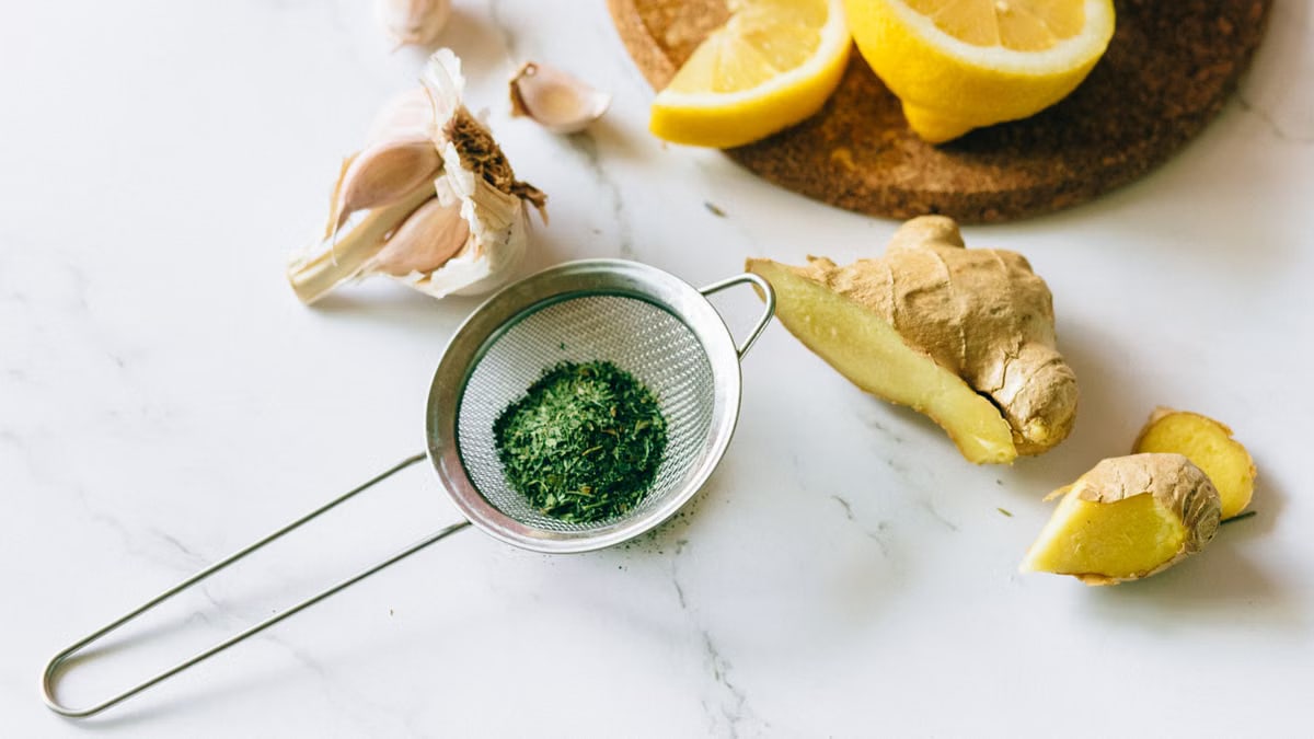 A flat lay of garlic, ginger, and lemon on a marble surface for natural remedies.